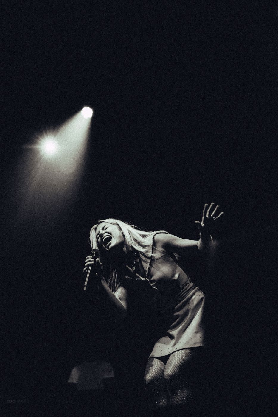 Black and white low-angle shot of a singer under a spotlight