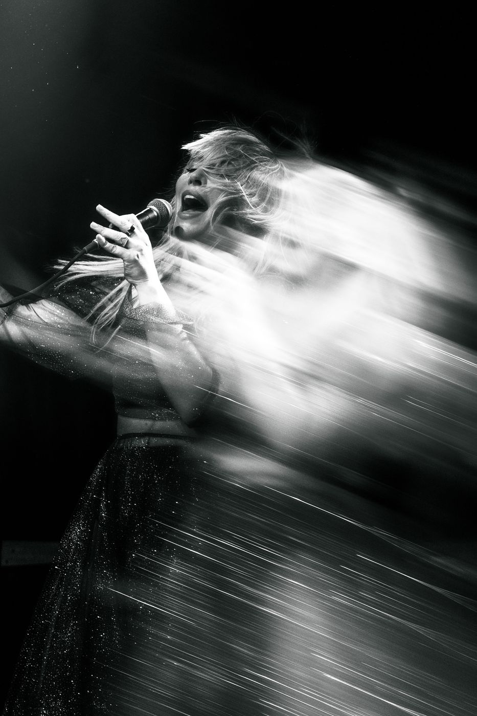 Black and white motion-blur portrait of a singer mid-performance