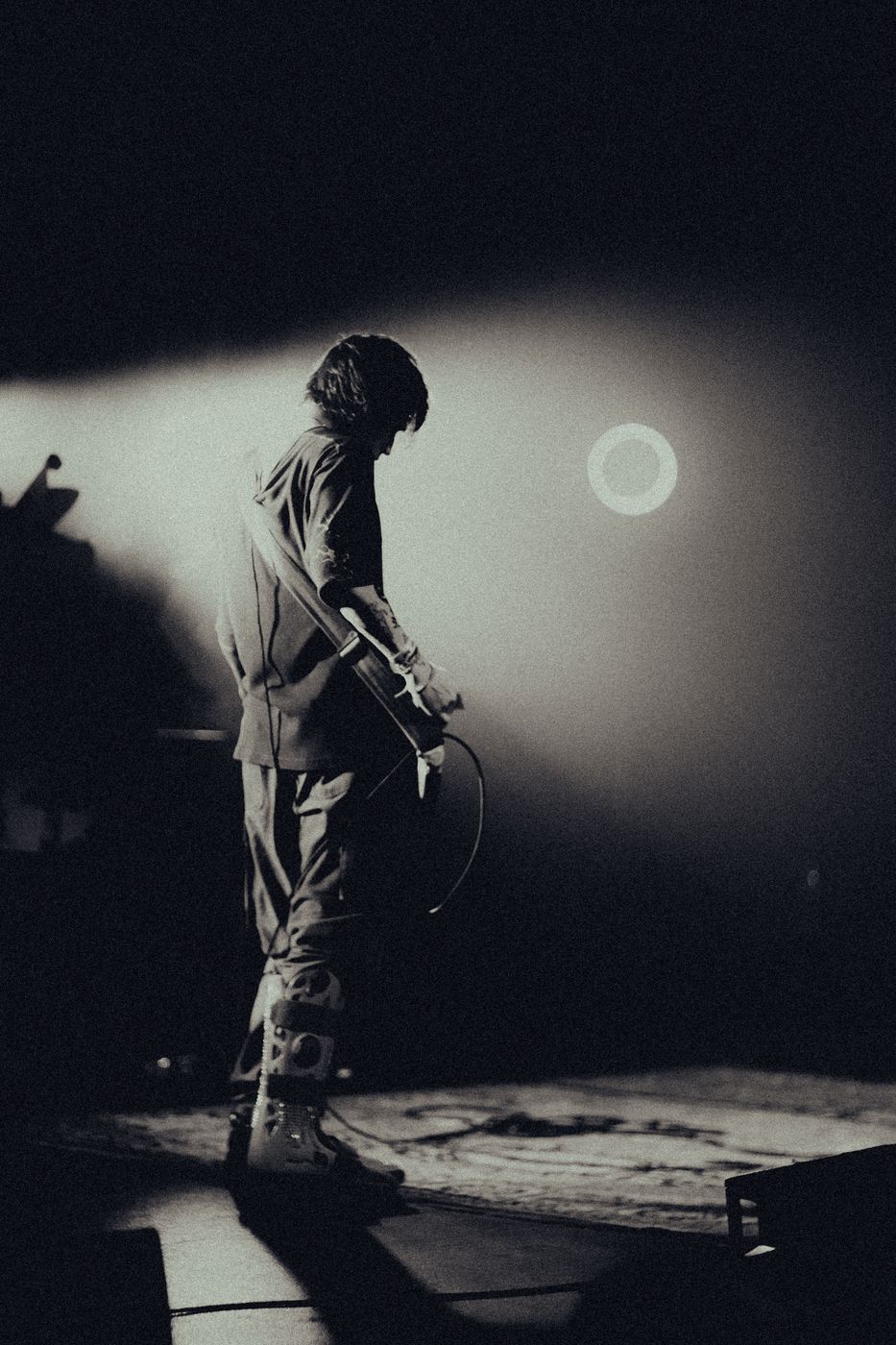 Backlit performer with wind-blown hair singing into a microphone