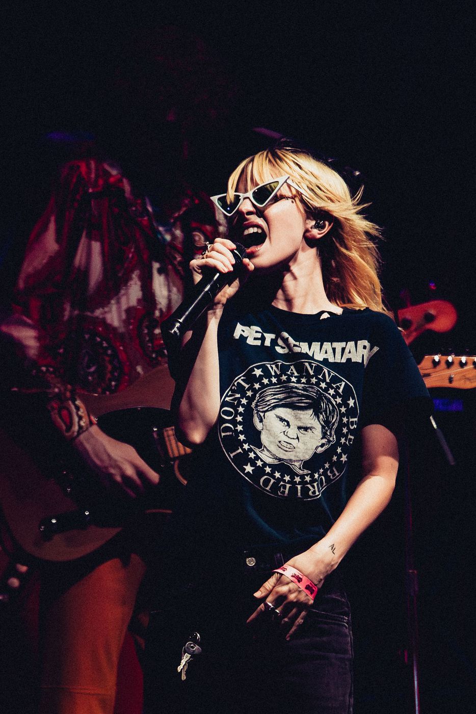 Singer in sunglasses performing under dark blue stage lighting