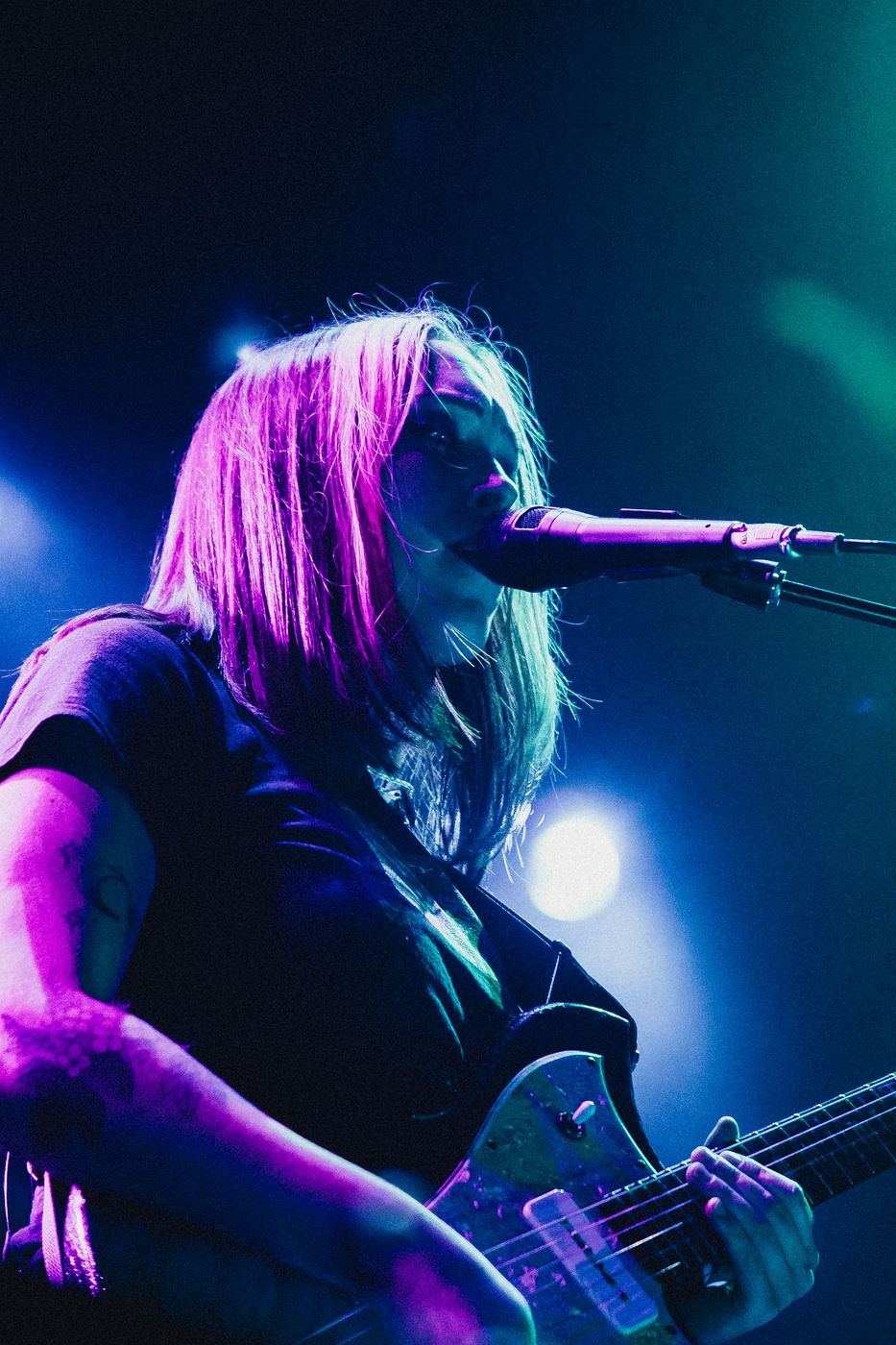 Singer performing under pink and purple stage lighting